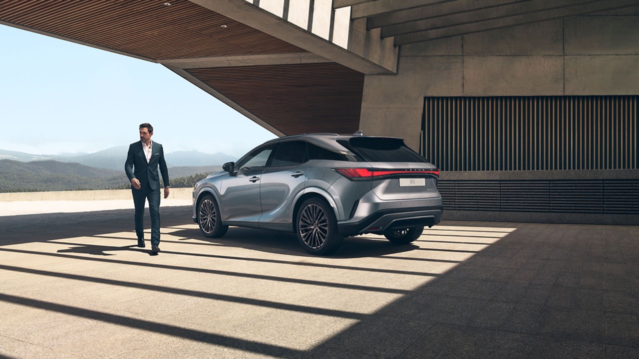 A man walking towards a parked Lexus ES