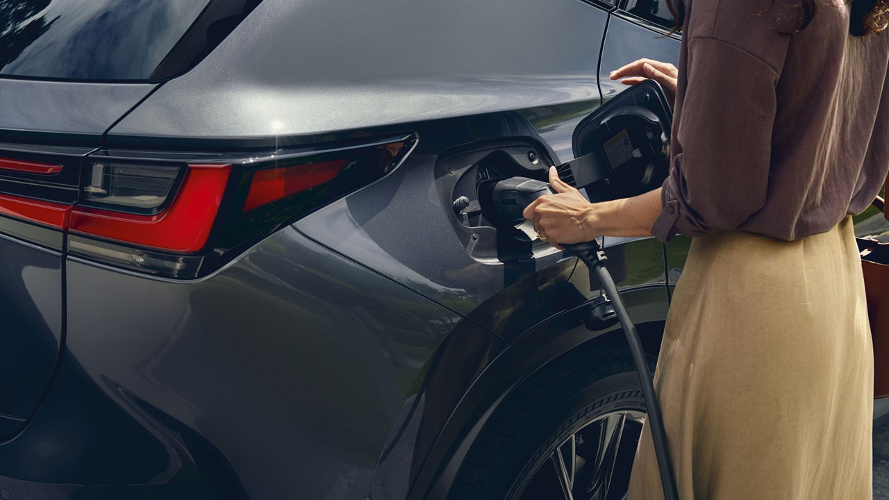 A woman using a home socket charger in a Lexus NX