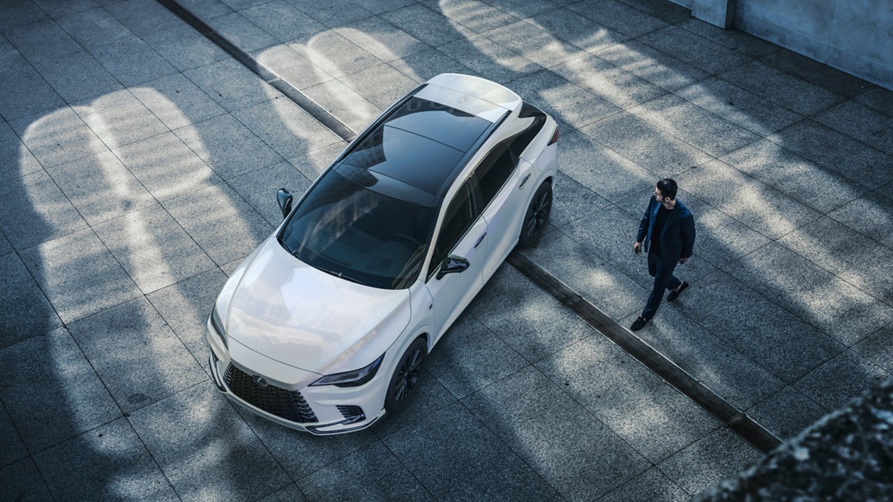 A man walking towards a Lexus
